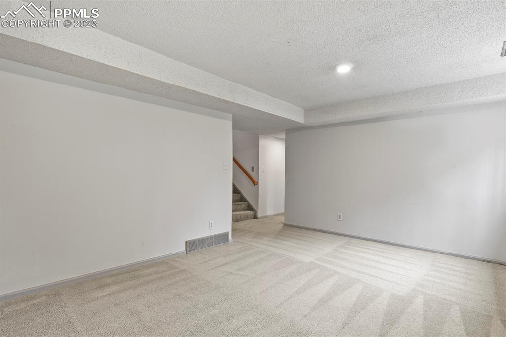 Image 23 of 39: Carpeted family room featuring stairs and a textured ceiling