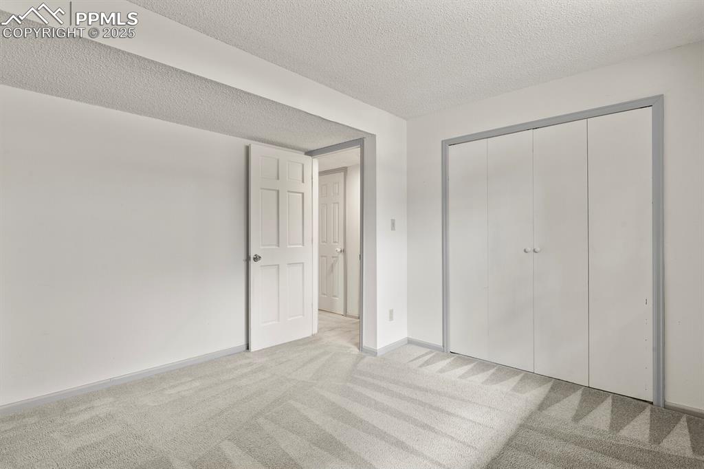Image 29 of 39: Unfurnished bedroom featuring light colored carpet, a textured ceiling, and