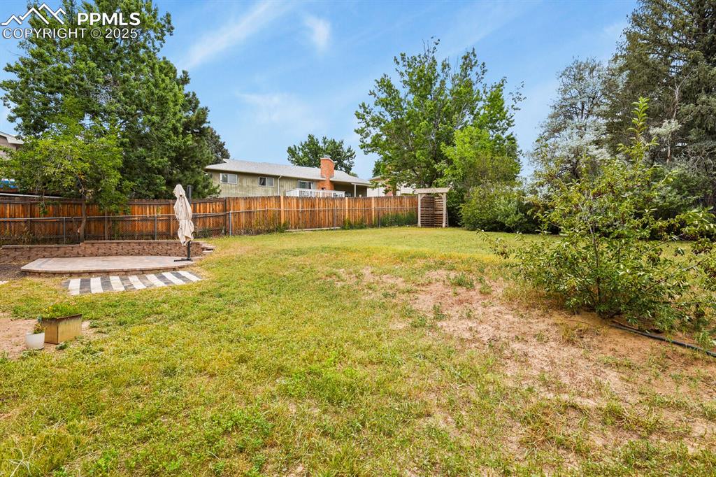 Image 38 of 39: Fenced backyard with a patio