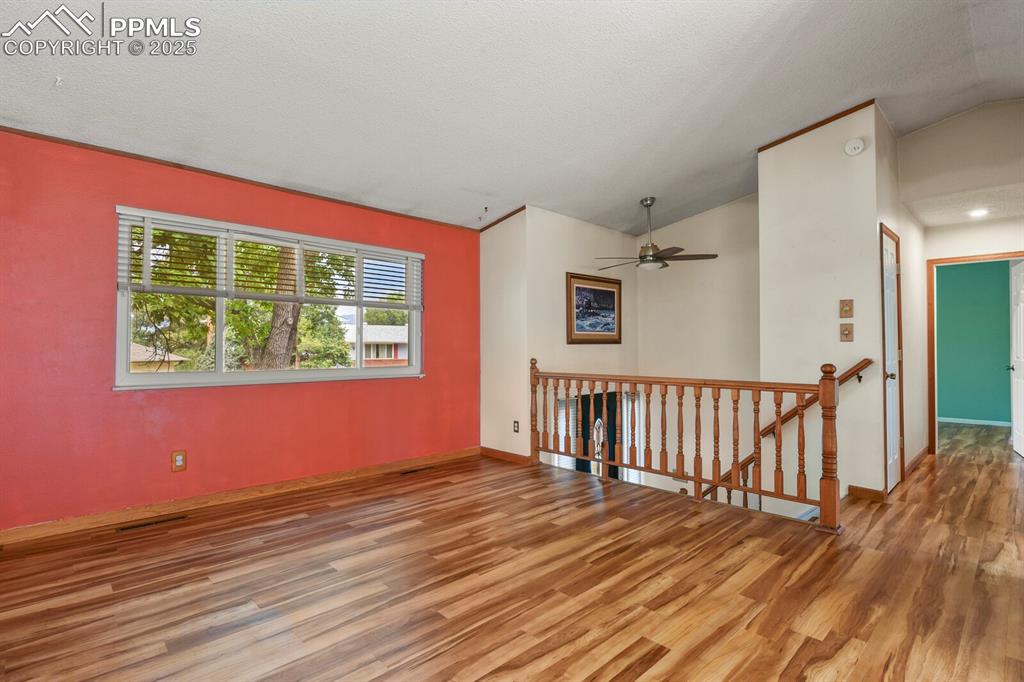 Image 6 of 39: Large living room with beautiful floors, vaulted ceiling, and ceiling fan