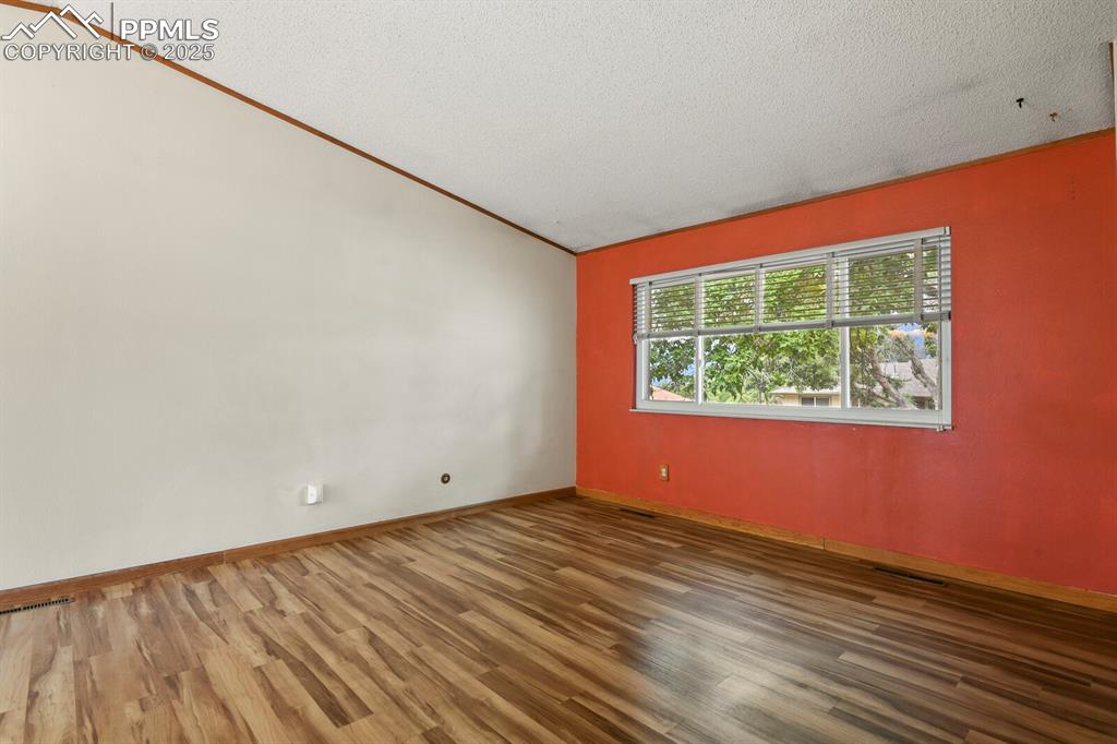 Image 8 of 39: Living room with vaulted ceiling, wood finished floors, and a textured ceil