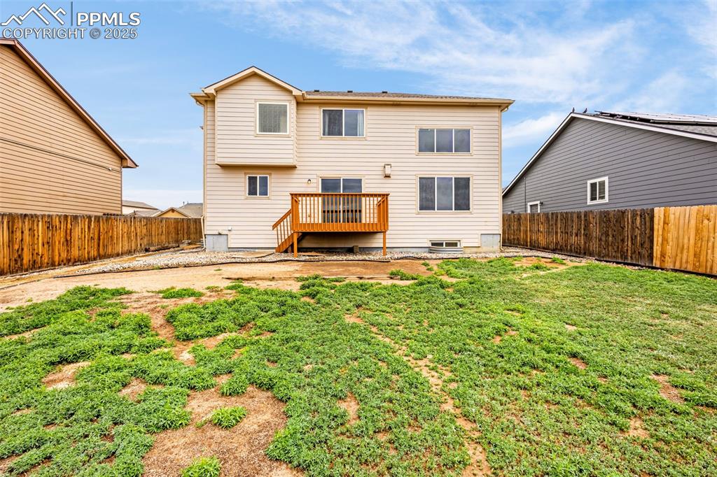 Image 4 of 39: Rear view of property with a yard, a deck, and a fenced backyard