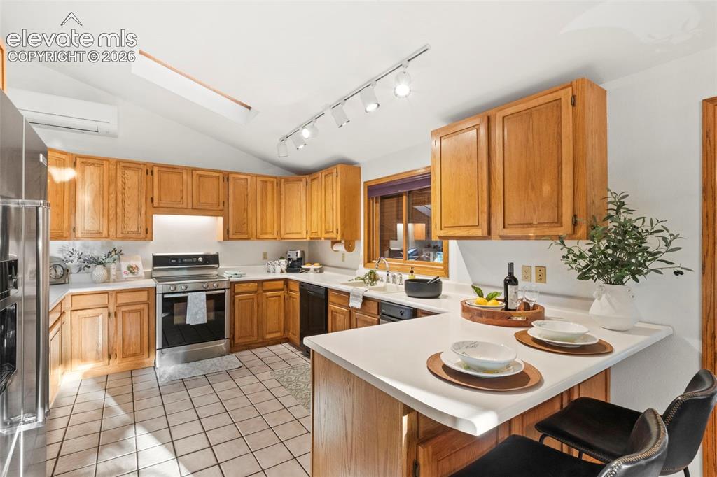 Image 10 of 47: Kitchen featuring wood cabinetry, solid-surface countertops, tile flooring,