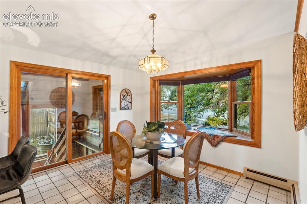 Image 13 of 47: Dining area featuring a bay window with wood trim, ceramic tile flooring, a
