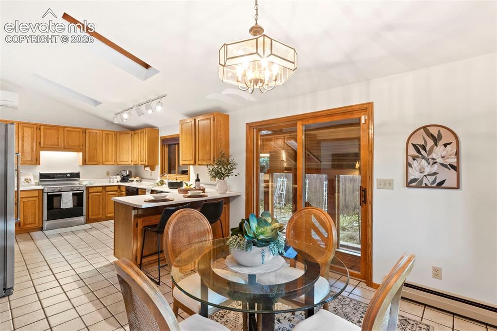 Image 14 of 47: Kitchen featuring wood cabinetry, solid surface countertops, a breakfast ba