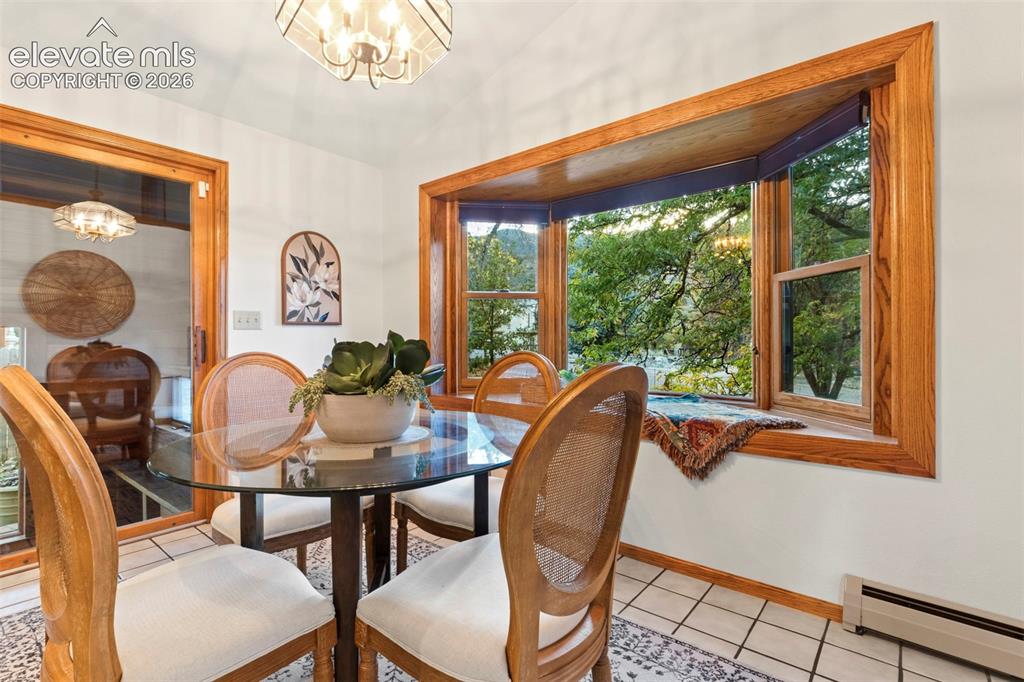 Image 15 of 47: Large bay window with wood trim, ceramic tile flooring, and geometric overh