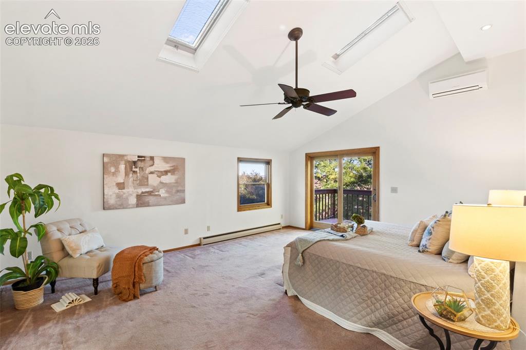 Image 19 of 47: Vaulted ceiling featuring dual skylights, ceiling fan, wall-mounted climate