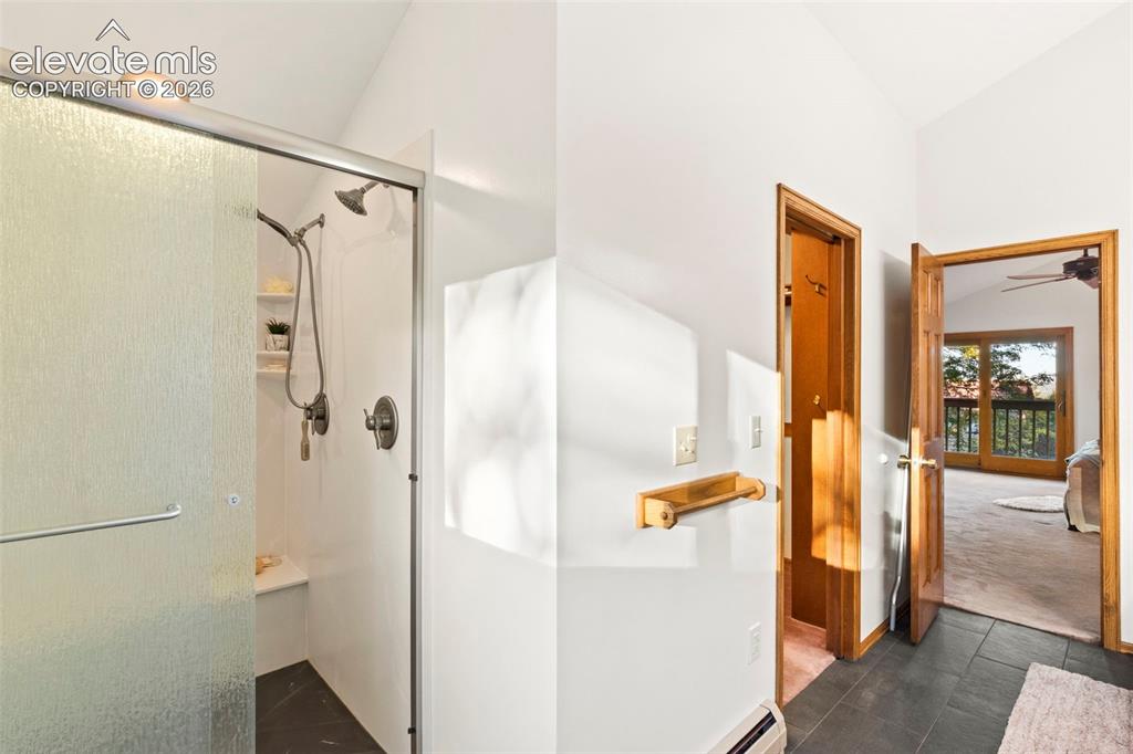 Image 20 of 47: Shower enclosure with glass door, handheld shower head, and built-in bench 