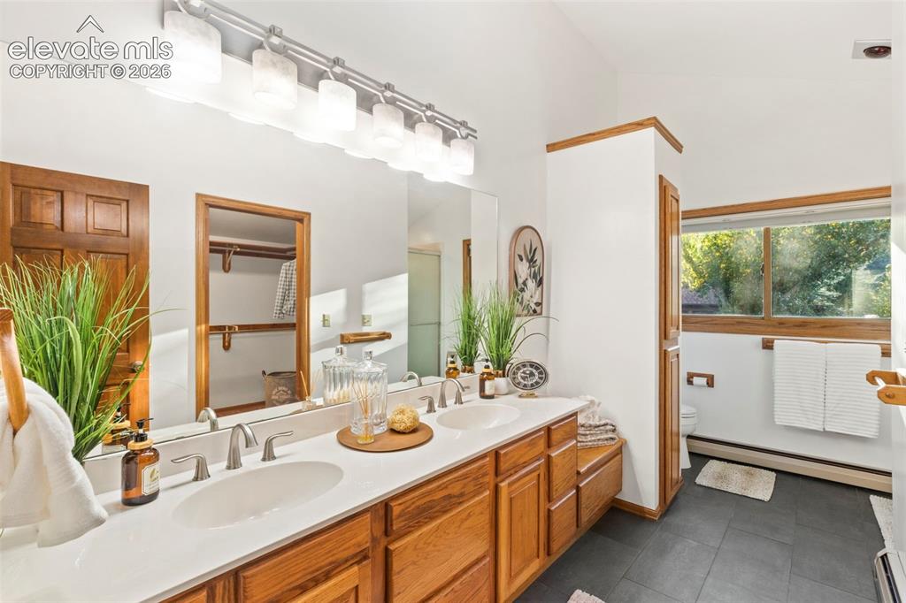 Image 21 of 47: Dual-sink vanity featuring light-toned solid surface countertops, natural w