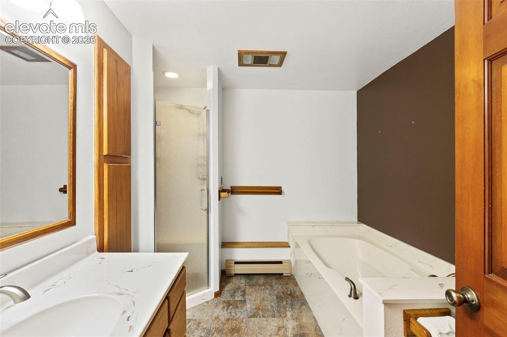 Image 25 of 47: Bathroom featuring a vanity with a white stone-patterned countertop, a sepa