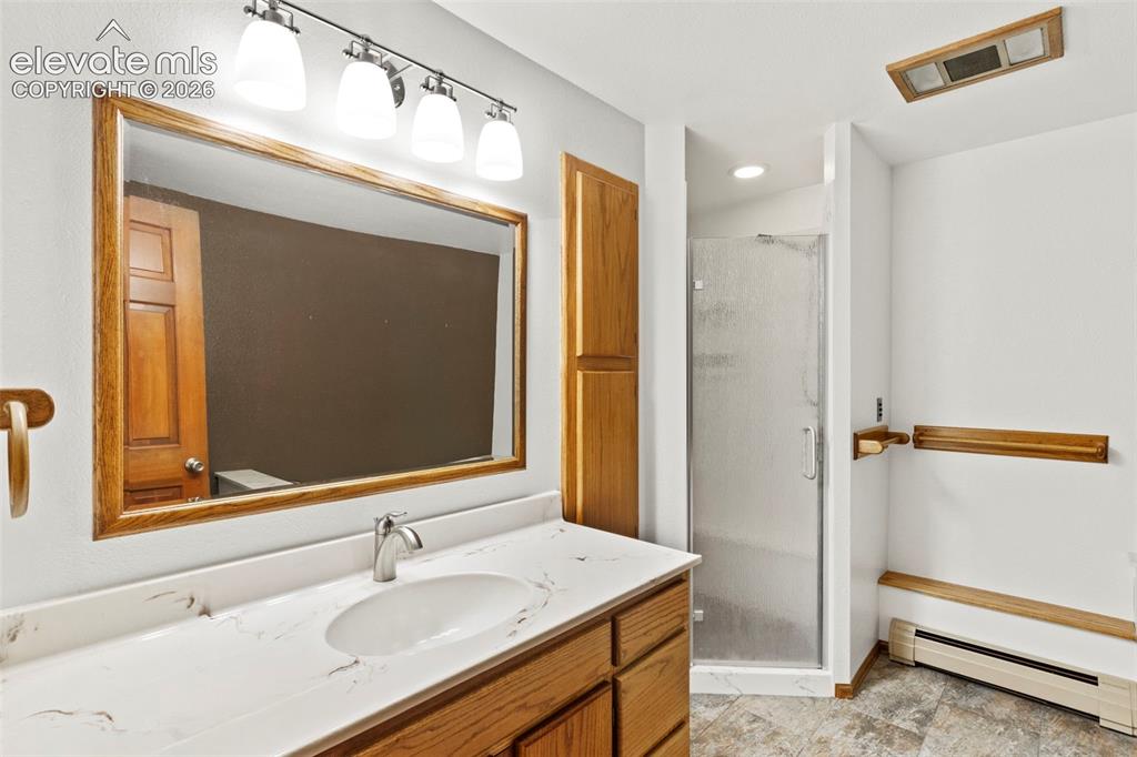Image 36 of 47: Bathroom featuring wood cabinetry, stone-surface countertop with an integra