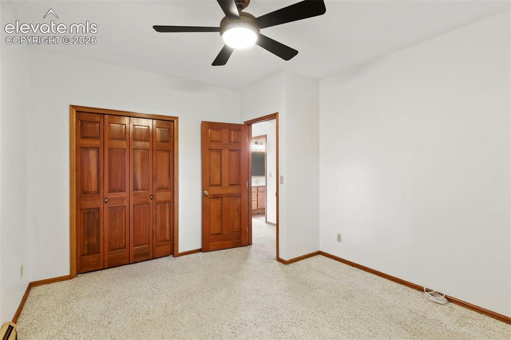 Image 37 of 47: Neutral-toned carpeting, wood-finish bi-fold closet doors, six-panel wood-f