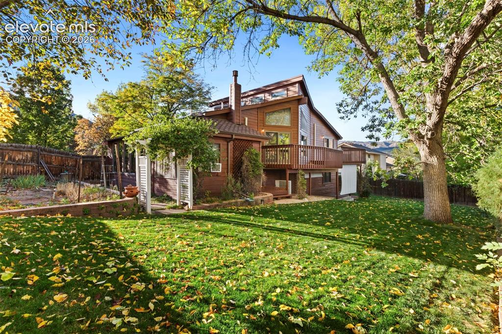 Image 4 of 47: Exterior featuring wood siding, expansive elevated wooden deck, stone retai