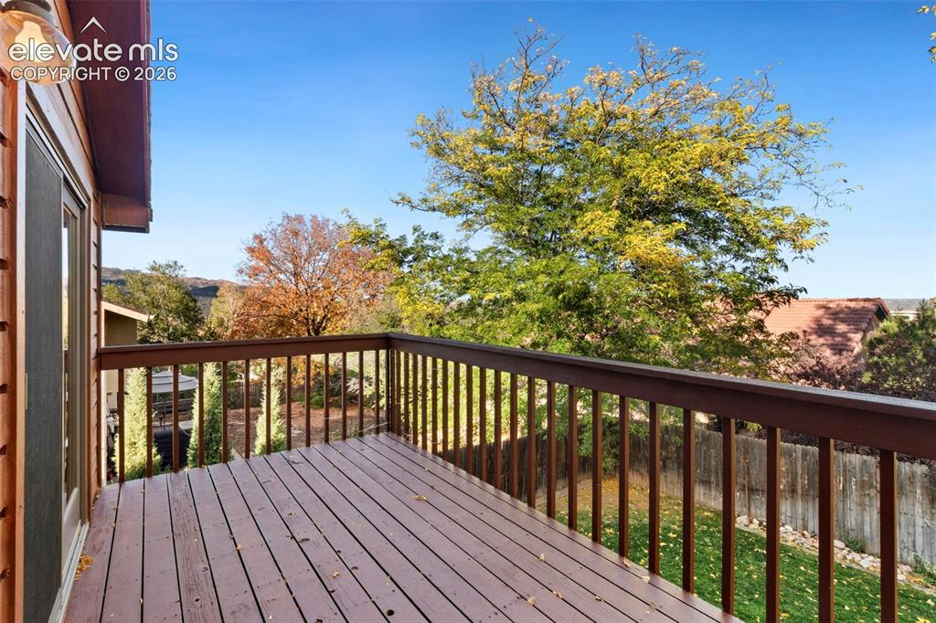 Image 45 of 47: Elevated wood deck featuring a painted wood railing and wall-mounted exteri