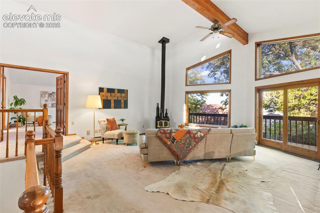 Image 7 of 47: Vaulted ceilings featuring an exposed wood beam, a freestanding wood-burnin