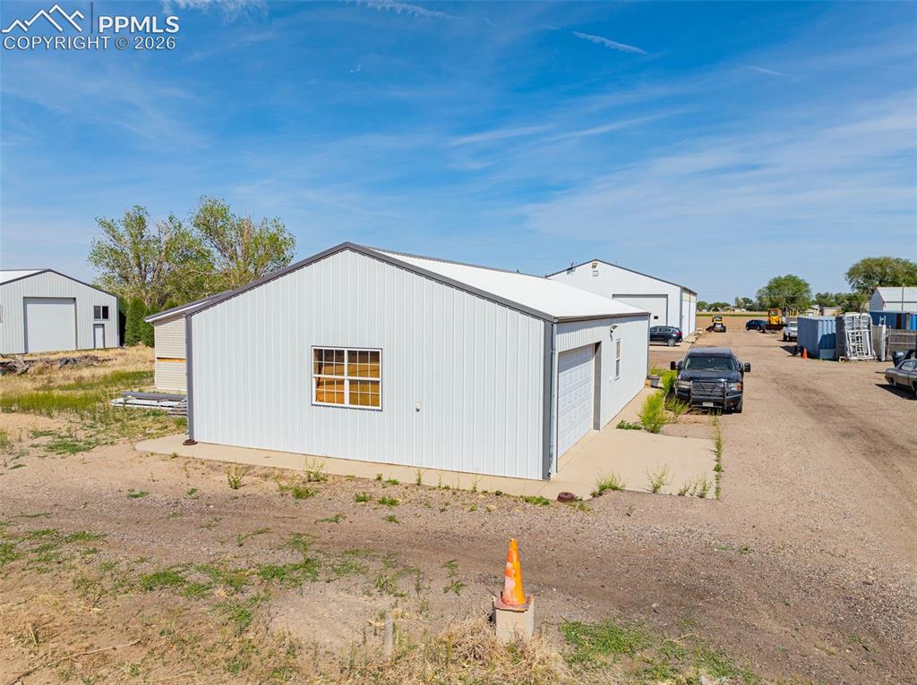 Image 11 of 20: Metal-sided building featuring a gable roof, a single window with grids, an