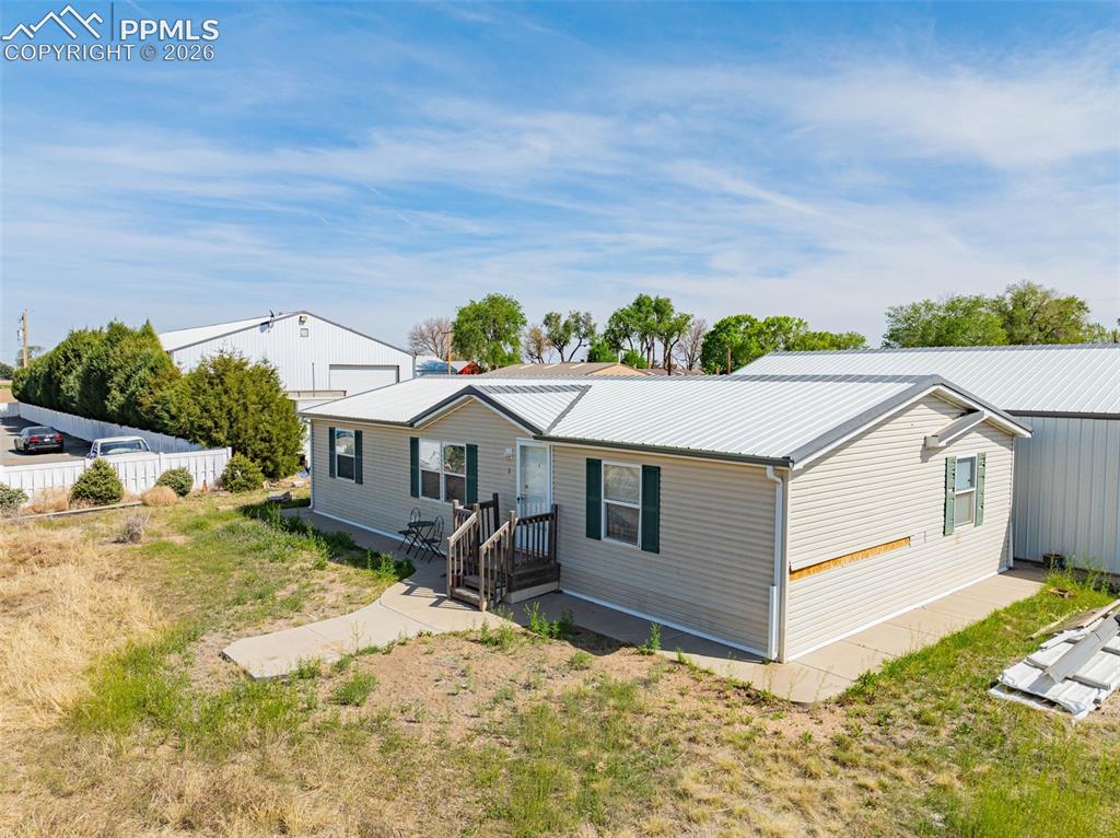 Image 9 of 20: Single-story residence featuring light-colored siding, a metal roof, and da