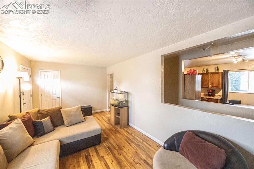 Image 4 of 21: Living area featuring wood finished floors, and a textured ceiling