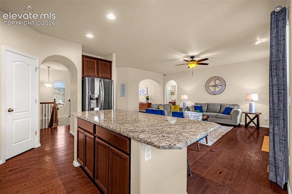 Image 12 of 49: Kitchen island with stone countertop and wood-finish cabinetry, stainless s