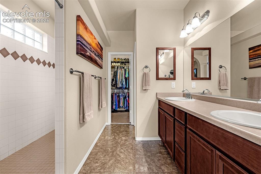 Image 19 of 49: Dual-sink vanity with wood-finish cabinetry, solid surface countertop, inse