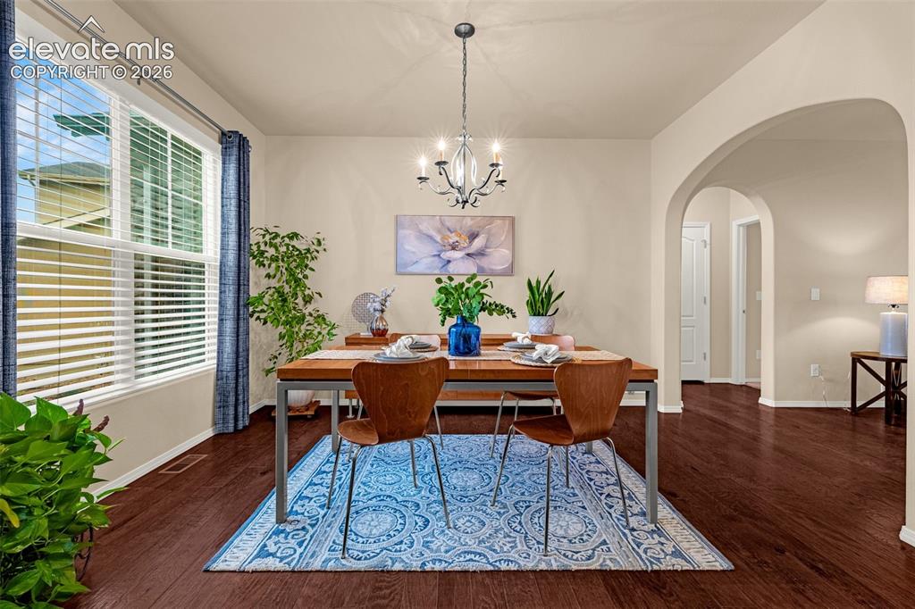 Image 2 of 49: Dining area featuring wood-finish flooring, a multi-arm chandelier, an arch