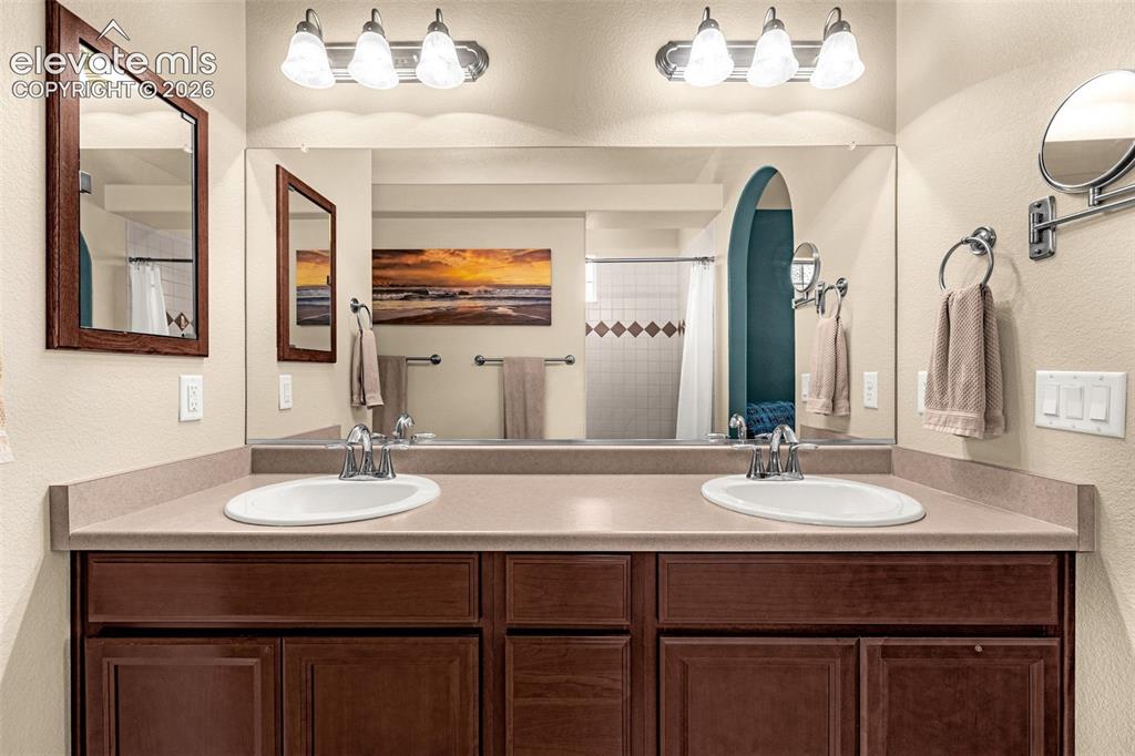 Image 21 of 49: Double-sink vanity featuring a solid surface countertop, wood-finish cabine