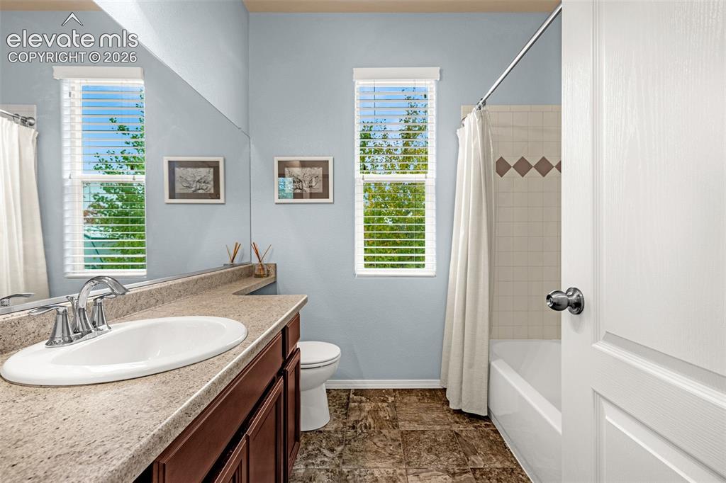 Image 26 of 49: Bathroom featuring an oval drop-in sink, stone-surface countertop, dark woo