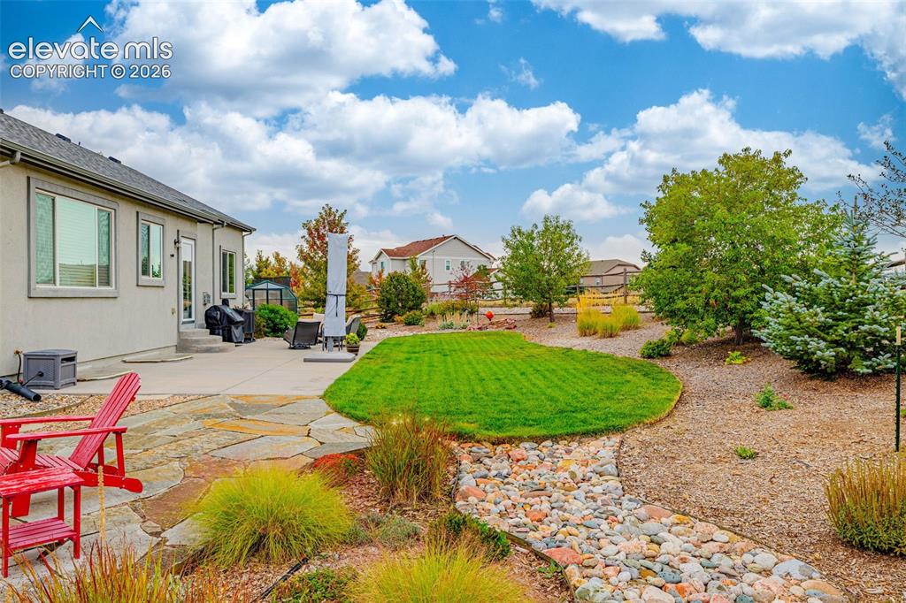Image 42 of 49: Stucco exterior featuring a flagstone patio, manicured lawn, decorative roc