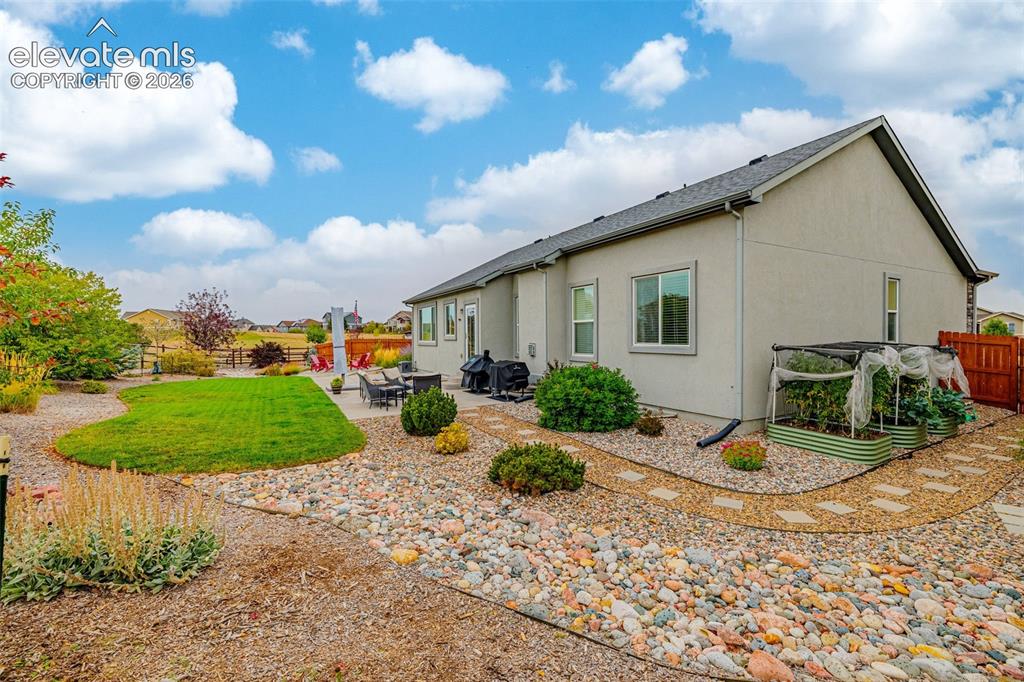 Image 44 of 49: Rear exterior featuring a concrete patio, xeriscaped grounds with river roc