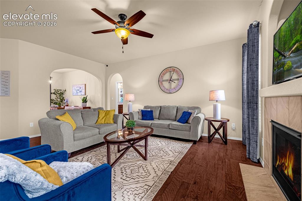 Image 8 of 49: Wood-finish flooring, fireplace with tile surround, arched architectural op