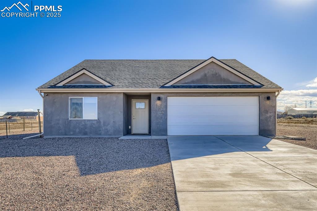 Caption: Ranch-style house featuring concrete driveway, roof with shingles, stucco siding, and an attached ga