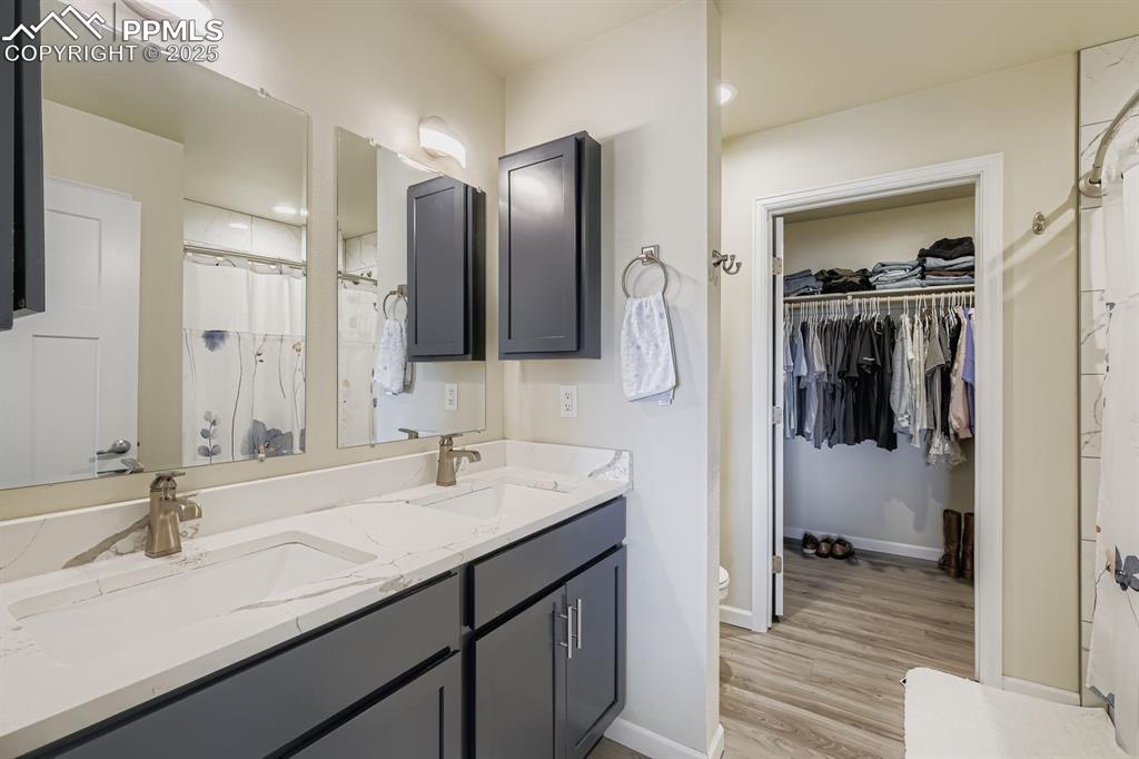 Image 14 of 23: Bathroom featuring a shower with shower curtain, double vanity, a walk in c