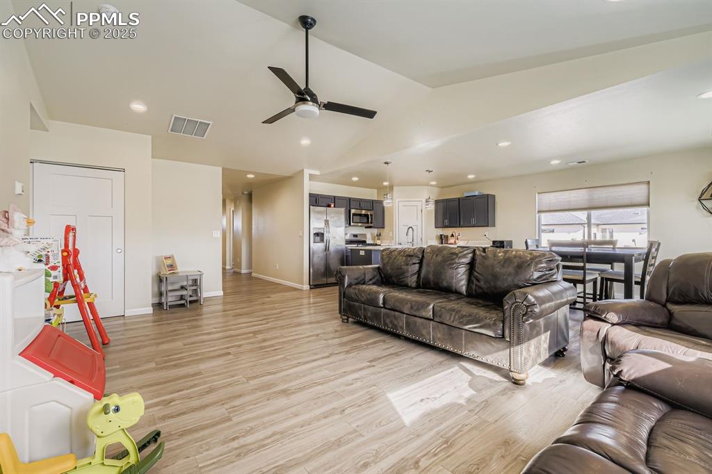 Image 4 of 23: Living room featuring light wood-style flooring, vaulted ceiling, ceiling f