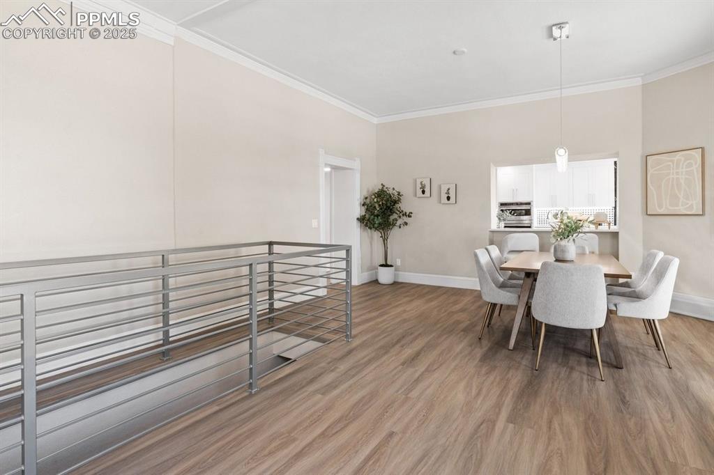 Image 11 of 50: Dining space with crown molding, light wood finished floors, and baseboards