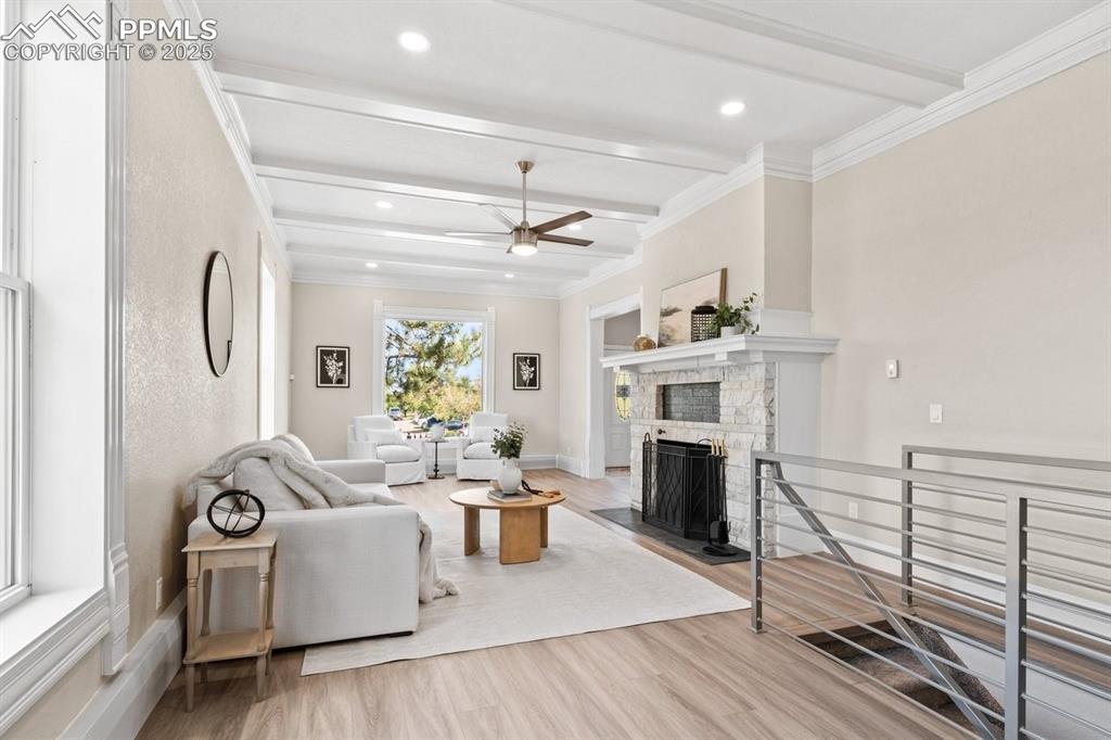 Image 14 of 50: Living room featuring beam ceiling, ceiling fan, wood finished floors, a fi