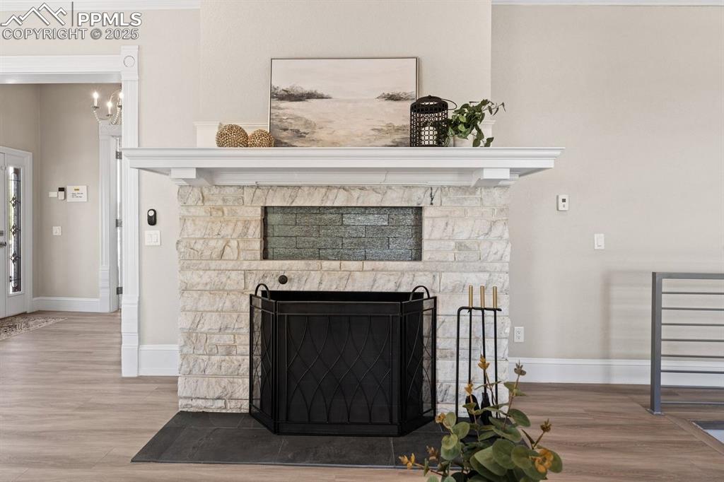 Image 16 of 50: Detailed view of a fireplace, wood finished floors, and baseboards