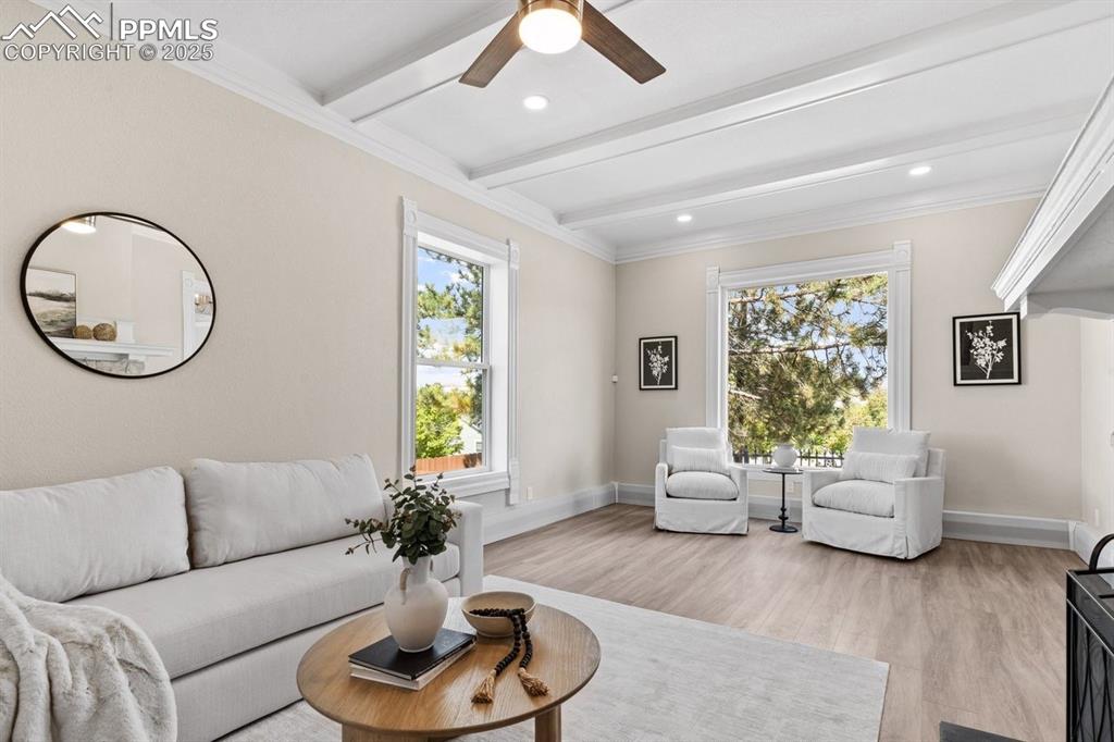 Image 18 of 50: Living area with light wood finished floors, beam ceiling, plenty of natura