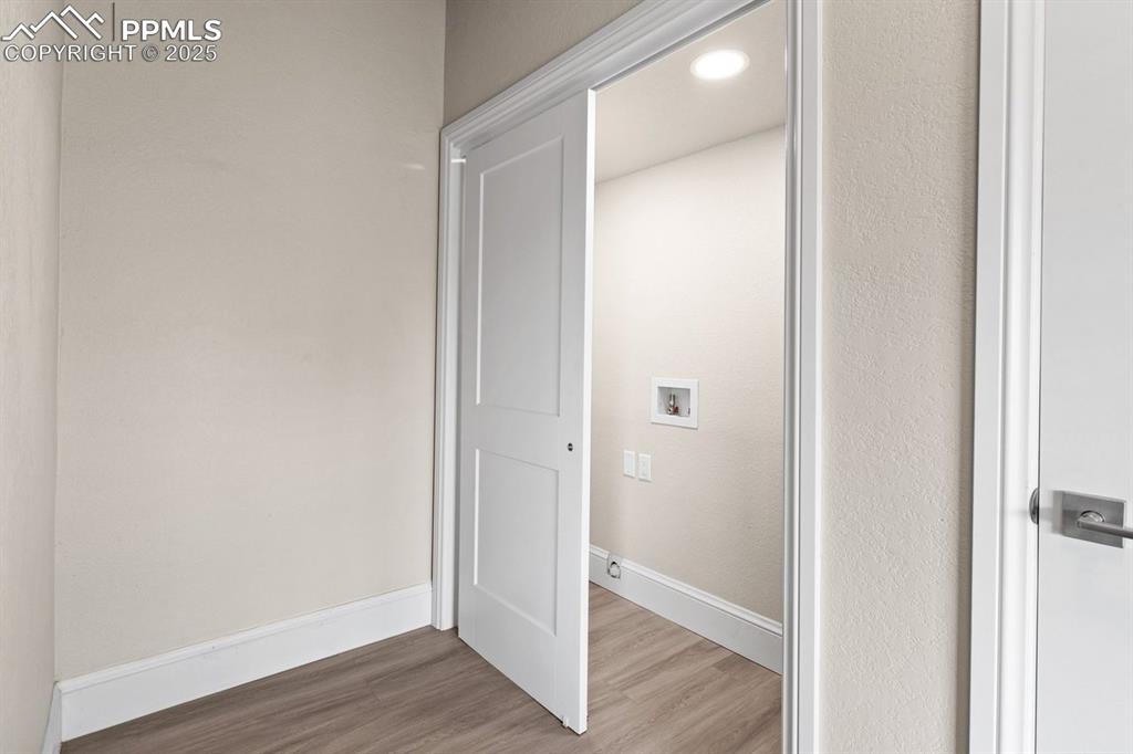 Image 21 of 50: Laundry area with washer hookup, wood finished floors, and baseboards