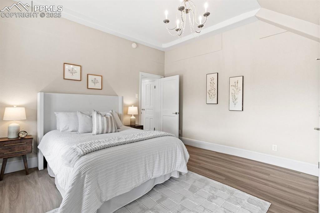 Image 22 of 50: Bedroom featuring a chandelier, light wood-style flooring, baseboards, and