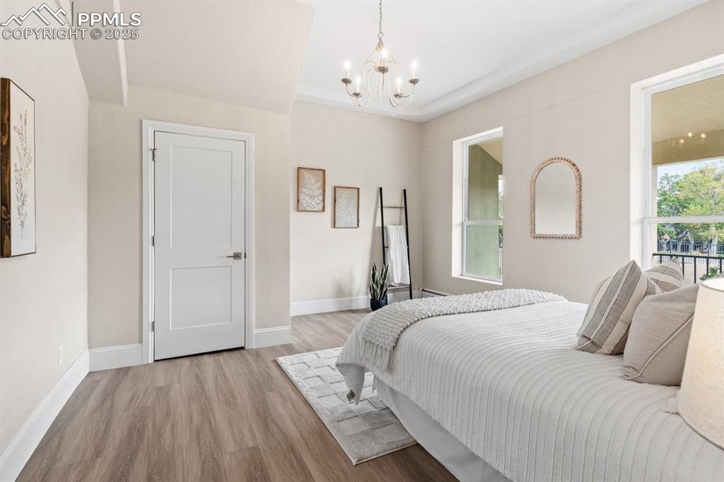 Image 23 of 50: Bedroom with a chandelier, wood finished floors, and baseboards