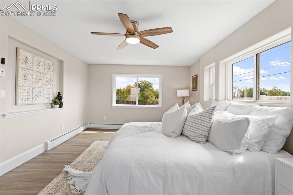 Image 25 of 50: Bedroom with a baseboard radiator, wood finished floors, baseboards, and a