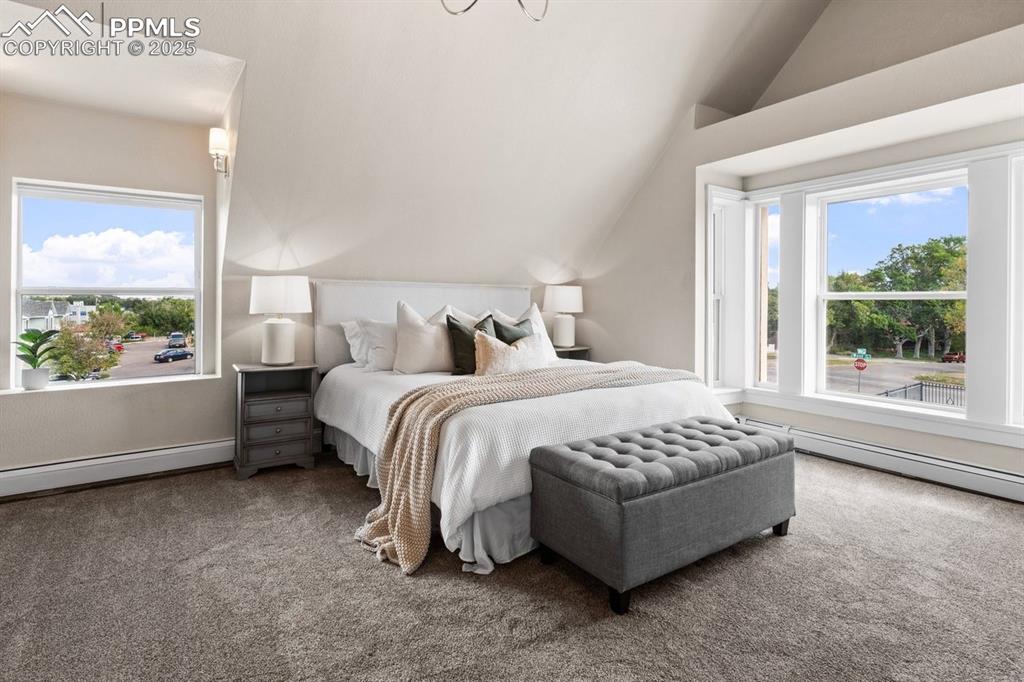 Image 31 of 50: Carpeted bedroom featuring lofted ceiling and a baseboard heating unit