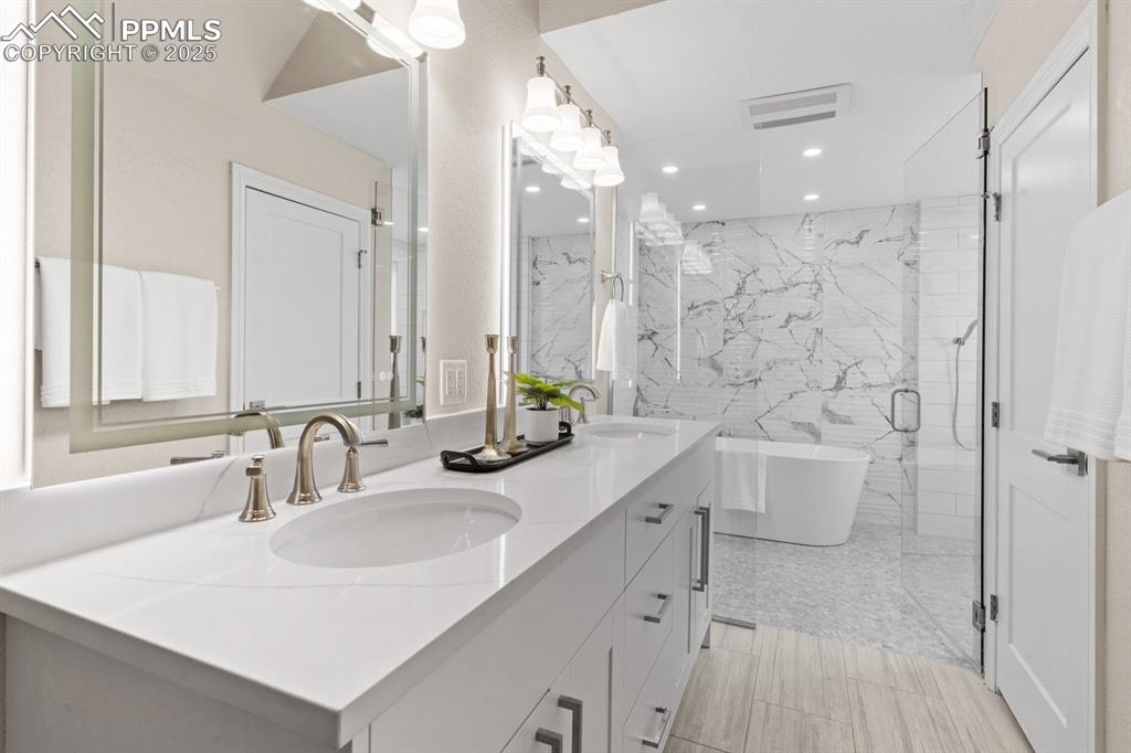 Image 34 of 50: Full bathroom featuring double vanity, a freestanding bath, recessed lighti