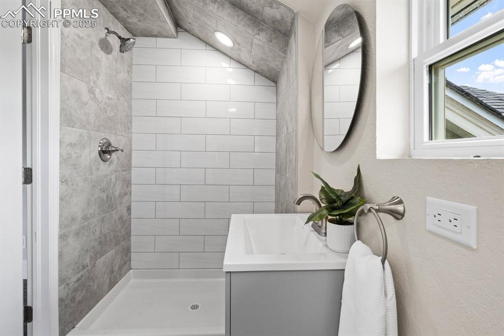 Image 39 of 50: Bathroom featuring tiled shower and vanity