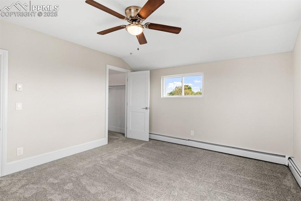 Image 40 of 50: Unfurnished bedroom featuring lofted ceiling, a baseboard radiator, carpet,