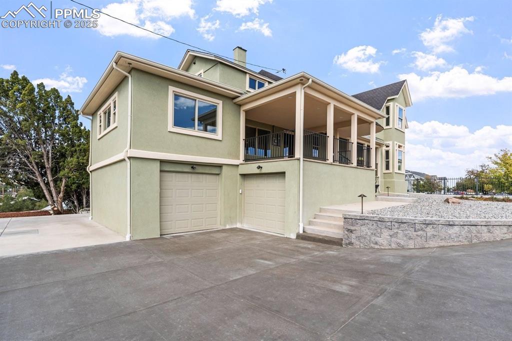 Image 44 of 50: View of front facade featuring stucco siding, a garage, and driveway