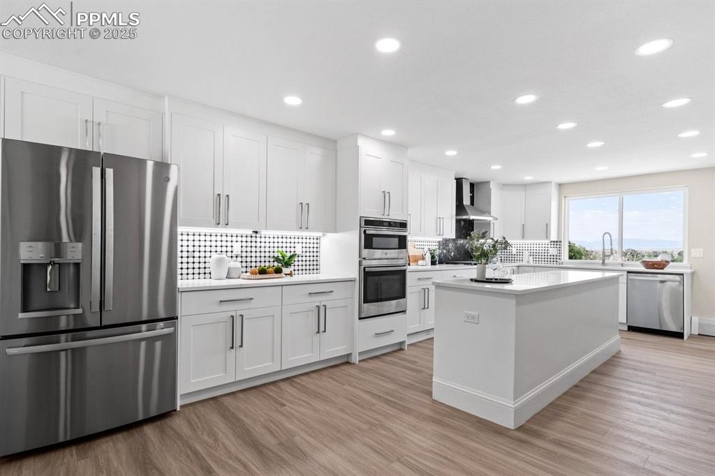 Image 8 of 50: Kitchen featuring appliances with stainless steel finishes, wall chimney ra