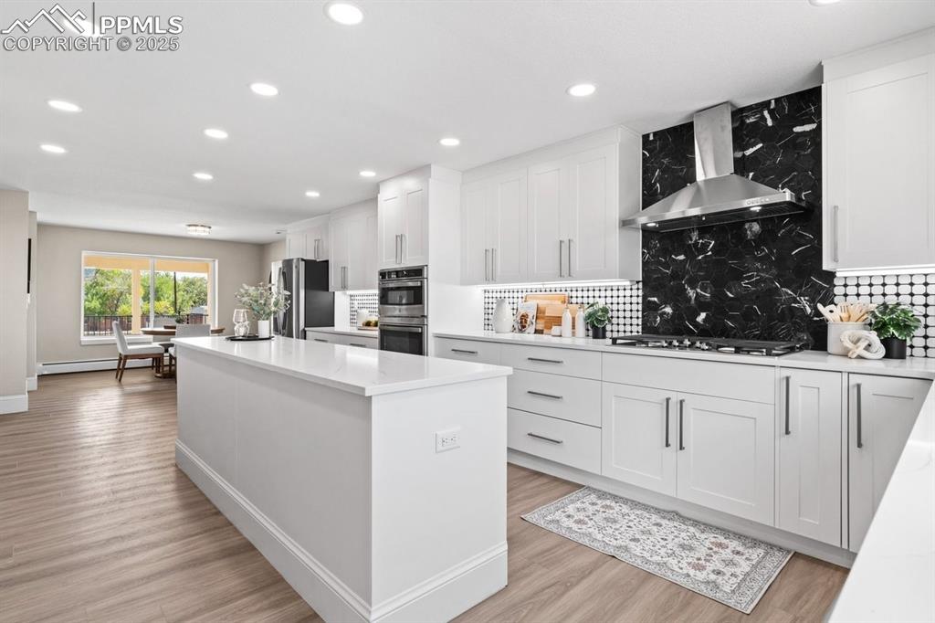 Image 9 of 50: Kitchen featuring wall chimney range hood, stainless steel appliances, a ce