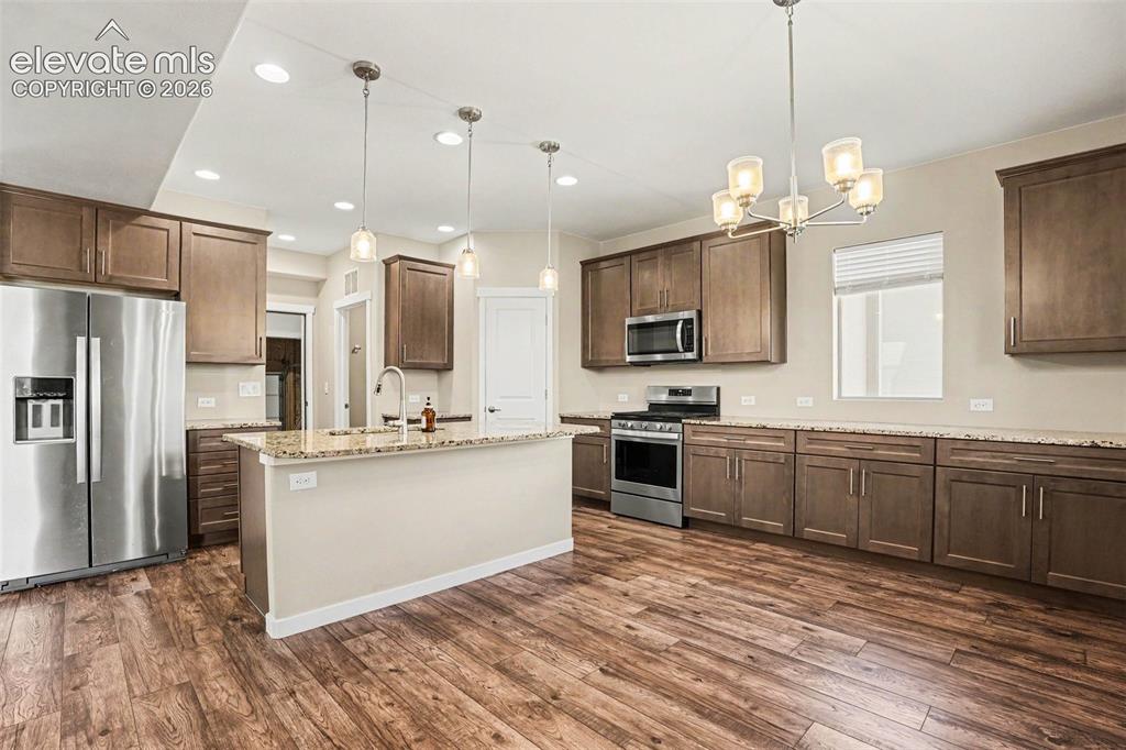 Image 10 of 27: Open-concept living area featuring wood-finish flooring, recessed lighting,
