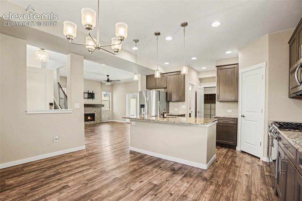 Image 12 of 27: Kitchen island with a granite countertop, undermount sink, and dark wood-fi